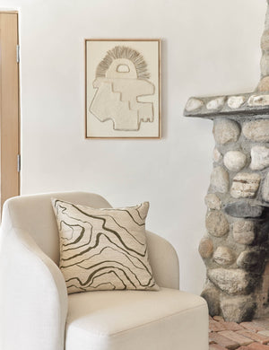 Canyon Olive Green Square Pillow sits on an ivory accent chair next to a stone fireplace