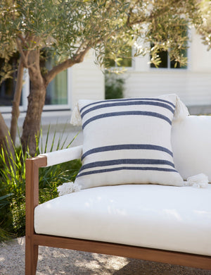 The Fez slate and white indoor and outdoor throw pillow sits on a white sofa in an outdoor space