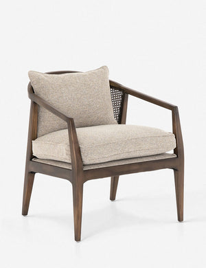 Angled view of Rhea accent chair with natural-toned cushions and curved wicker back