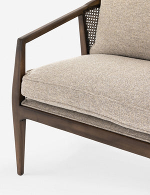 Close-up of the left side of the Rhea accent chair with natural-toned cushions and curved wicker back