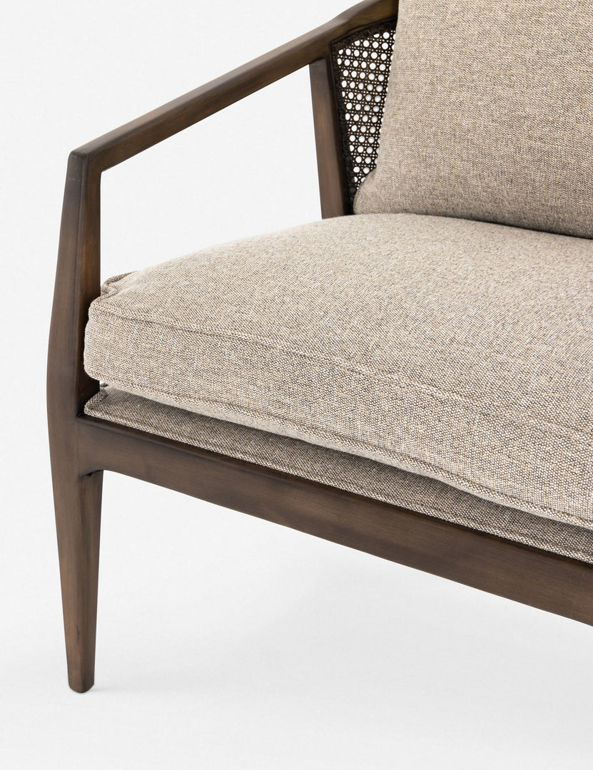 | Close-up of the left side of the Rhea accent chair with natural-toned cushions and curved wicker back