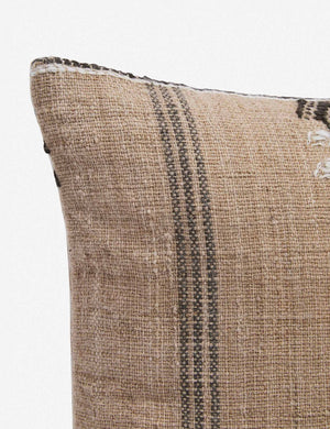 Corner of the Rica taupe square throw pillow with blue, white, and black woven arrow-like designs
