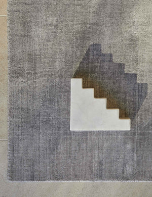Bird's-eye view of the corner of the gray dylan rug with a staircase shaped white sculptural object sitting atop it
