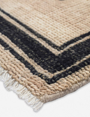 Close-up of the edge of the Senna neutral hand-knotted wool area rug with black geometric pattern