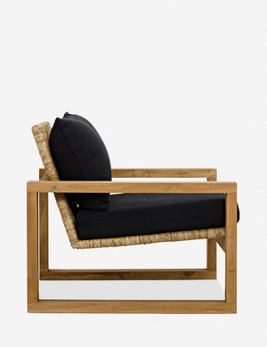 Side view of the Regine wooden accent chair with black cushions and rattan detailing