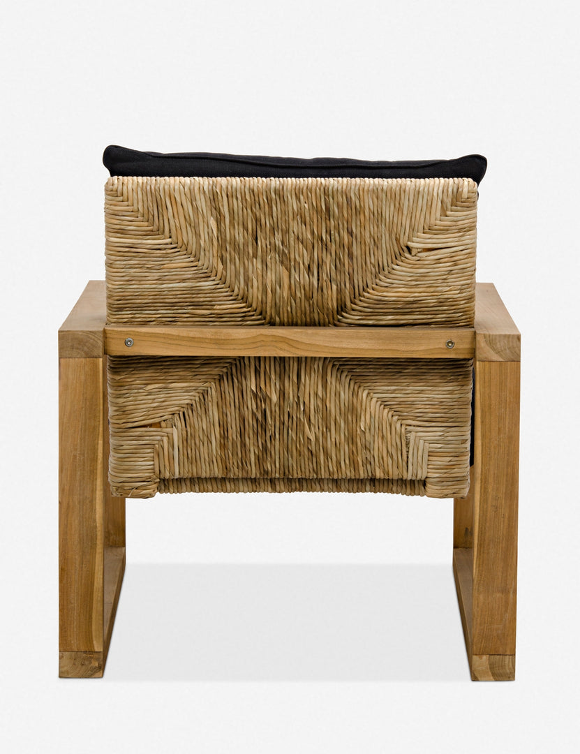 | Rear view of the Regine wooden accent chair with black cushions and rattan detailing, showing the woven cane and rattan detailing on the back of the chair