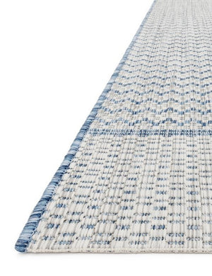 Angled close-up of the edge of the Sonya gray and blue geometric indoor and outdoor rug