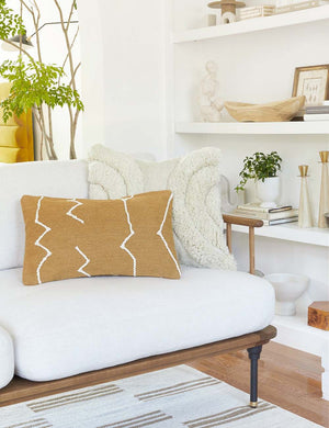 The moroccan ochre and natural beni ourain inspired lumbar flat weave pillow by Sarah Sherman Samuel sits atop a white linen sofa