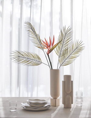 Kala matte white geometric vase by light and ladder sits on a white washed wooden dining table with ribbed water glasses