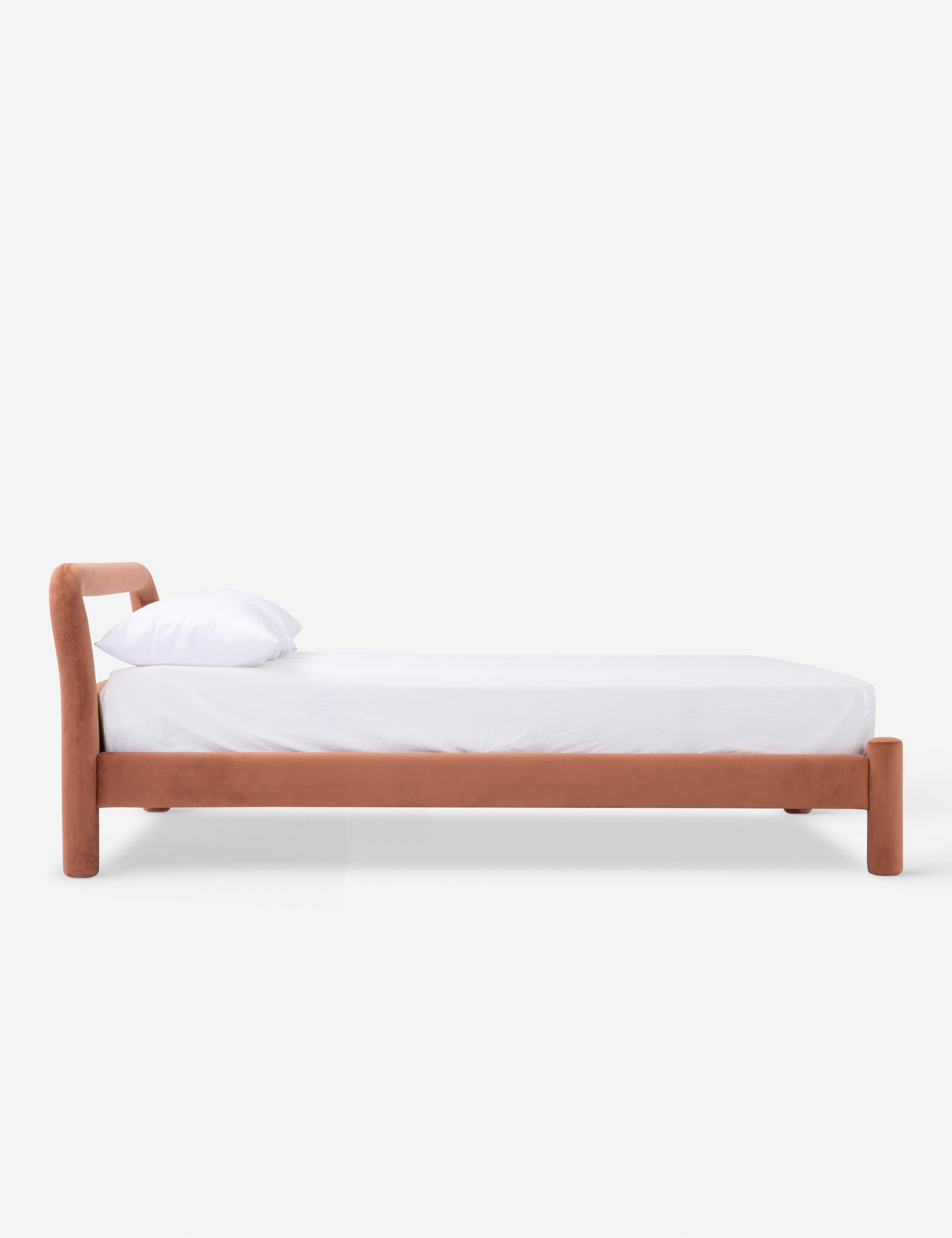 Another view of the black upholstered bed with curved headboard and cylindrical legs, with white bedding.