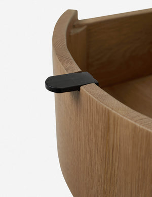 Close-up of the black tab drawer pull with the drawer opened on the Kono round solid oak nightstand with one drawer