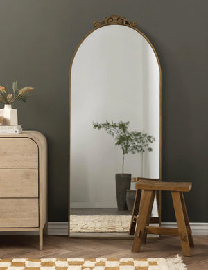 The tulca narrow floor mirror sits against a wall next to a checkerboard rug, a white dresser, and wooden stool