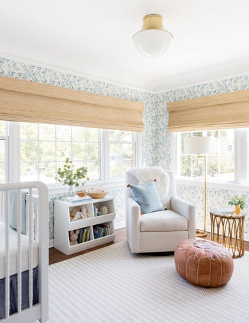 #showall::39489938817123 | The Randi curved brass Flush Mount Light with domed glass cover is mounted in a nursery with floral wallpaper, white furniture, and a leather ottoman