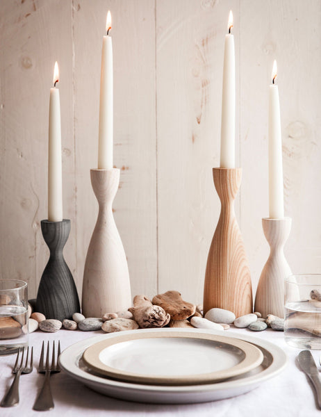 #size::small #size::medium #color::natural #color::grey #color::white | The Pantry wooden candlesticks with smooth curves by farmhouse pottery in gray, neutral, and white sit on a dining room table with neutral dinnerware